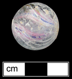 18QU124 - Handmade glass marble in a variety known as solid core swirl. Dates from the 1850s through at least the 1890s (Gartley and Carskadden 1998:127-129). Cut-off marks visible at either “pole” of the marble (along the marble edges at the left and right center on this photograph) - click on image to see larger view.